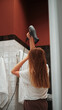 © Iryna - A young woman with light brown hair is blow-drying her hair after a shower