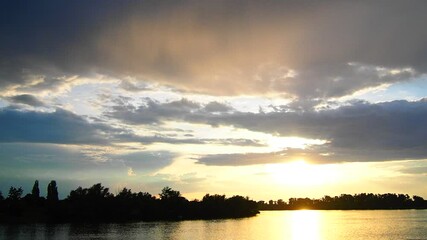 Poster - Experience the captivating beauty of a halo sun shining brilliantly over a peaceful lake, surrounded by lush trees and dynamic cloud formations at twilight. Nature reveals its magic. River Sava Serbia