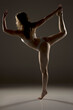 © vladimirfloyd - Silhouette of woman performing dancer pose (Natarajasana) yoga position, showcasing balance and flexibility in dramatic side lighting against dark background