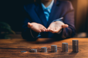 Poster - Businessman Showing Hands with Stacks of Coins on a Table Indicating Financial Growth and Investment Strategy