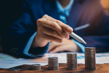 Poster - Businessman Analyzing Financial Growth with Stacks of Coins and Pen in Modern Office Setting
