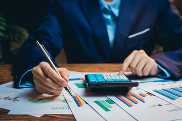 Poster - business professional analyzing financial graphs while using calculator during office meeting for st