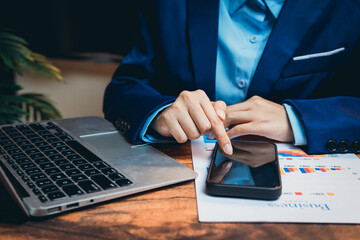 Poster - Business Professional Using Smartphone While Analyzing Reports on a Wooden Desk with Laptop and Plant