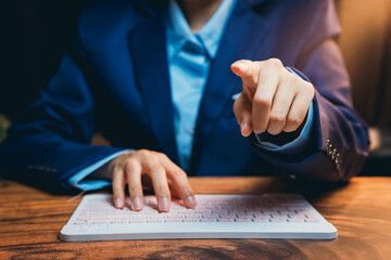 Poster - Business professional in suit typing on keyboard and pointing gesture with determination in modern office setting