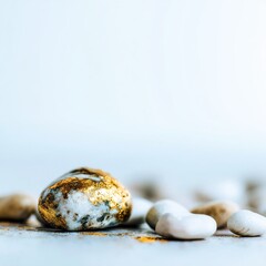 Poster - Gold leaf on rock close-up studio shot of gilded stone among pebbles on neutral surface with soft light and shallow depth of field