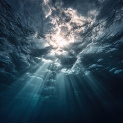 Poster - Underwater view of sun rays shining through ocean surface creating ethereal light beams in deep blue sea waters