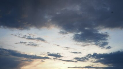 Poster - Witness the breathtaking transformation of the sky at dusk as the sun sets below the horizon, casting warm colors across billowing clouds in a tranquil landscape that inspires wonder