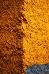 Poster - Close up of a golden yellow wall with rough texture and a dark grey area at the bottom in sunlight