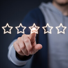 Poster - Person rating with glowing stars using their finger on a dark background close up shot in studio light