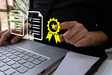 Poster - A person sits in front of their laptop, pointing at an icon of a yellow ribbon with black check marks over two documents floating in the air next to it.