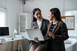 © Crystal - Two asian businesswomen are discussing working using laptop and document file in modern office