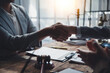 © Crystal - Lawyers shaking hands after signing a legal contract in their office, with legal documents and a gavel on the table