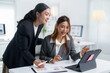 © Crystal - Two asian businesswomen are discussing and analyzing charts on digital tablet and paperwork in modern office