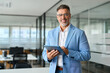 © insta_photos - Happy professional businessman ceo, older corporate leader executive manager in his 50s looking at camera. Confident mature business man investor wearing suit standing in office holding tab, portrait.
