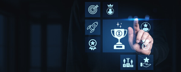 Poster - Businessman touching glowing digital award trophy icon with futuristic achievement and success symbols on dark blue interface background concept.