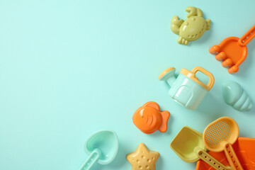 Colorful plastic beach toys flat lay on blue background with copy space