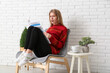 © Pixel-Shot - Emotional young woman reading newspaper on chair at home