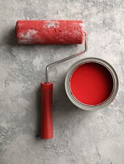 Poster - Paint Can and Roller Ready for Use on Clean Concrete Background With Vibrant Red Color for Home Improvement or Artistic Projects