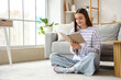 © Pixel-Shot - Young woman reading book on carpet at home
