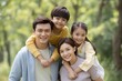 © Dzikrul Husnani - Happy Family Portrait: Joyful Children on Parents' Shoulders in a Serene Park