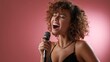 © สรศักดิ์ ธรรมวงษ์ษา - Joyful Woman with Curly Hair Singing into Microphone Against Pink Background