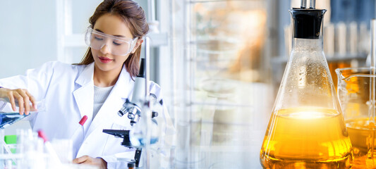 Wall Mural - attractive scientist woman testing chemical sample in flask at laboratory with lab glassware backgro