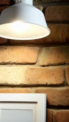 Poster - Interior scene featuring a lit white lamp, a framed blank white canvas, and an exposed brick wall, creating a rustic atmosphere.