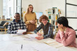 © Mediaphotos - Students engaging in group study session reviewing foreign languages with materials and textbooks around large table. Instructor standing nearby, assisting and smiling