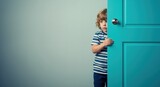 Young boy peeking from behind a turquoise door in a minimal room