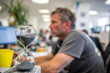 © Deny - Hourglass Sand Timer in Office Setting with Person Working