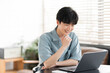 © lielos - 若い日本人男性がノートパソコンを開き作業をしている。