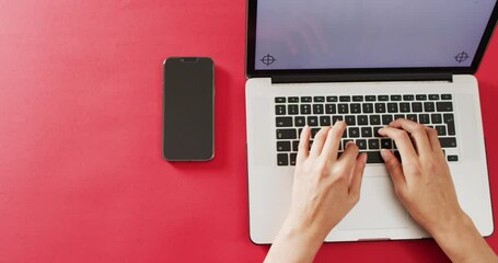 Poster - hands using laptop with smartphone on red desk with copy space