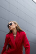 © MaxFrost - High fashion photo of a young blond woman in red suit, jacket, pants, and sunglasses. Monochrome trendy red outfit.