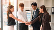 © saltdium - A diverse group of business professionals putting hands together in a gesture of teamwork, support, and unity during an office meeting
