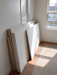 Poster - Drywall Panels Leaning Against Wall in Empty Room With Natural Light Illuminating the Space