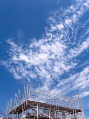 Aufkleber - Scaffolding Structures Rise Under a Clear Blue Sky With Bright Clouds During Daytime Construction Activities