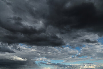 Wall Mural - Epic Dramatic storm dark grey black cumulus rain clouds against blue sky background texture, thunderstorm