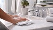 © Екатерина Канунников - A person is using a rag to clean the white marble countertop under their bathroom sink, which has a chrome faucet and matching silver handle