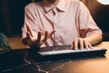 Poster - Person Gesturing with Hand While Using Keyboard in Modern Office Environment at Night