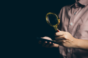 Poster - person holding magnifying glass and smartphone in dark setting, exploring details and information fo