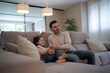 © asier - Father and daughter watching tv, enjoying family time on sofa