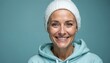 © Maryna - Portrait of smiling bald woman. Woman wears white beanie, blue hoodie, smiles confidently, projects hopeful outlook. Cancer patient, alopecia patient, celebrating recovery, remission, strong, happy.