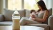 © Maryna - Feeding bottle filled with milk on table. In background mother hugs newborn baby on sofa. Tender caring mom breastfeeding baby. Soft lighting home atmosphere, parenting, infancy, maternity, love,