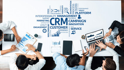 Fototapete - A dynamic business meeting focused on customer relationship management takes place around a table, with team members engaged in discussions using digital devices and charts. Amity