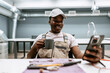 © fotofabrika - Man in work attire enjoys coffee while looking at phone in modern workspace during afternoon hours