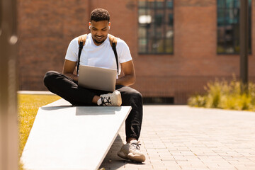 Aufkleber - Freelance concept. African american man using laptop computer, studying or working outdoor, typing on pc computer keyboard while sitting in city park, free space