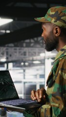 Poster - Vertical video Military technician in data center monitoring warfare drone telemetry on laptop dashboard. IT specialist in army server room using tactical interface on notebook to support aerial