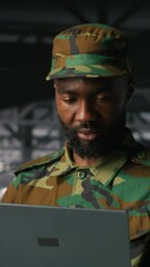 Poster - Vertical video Army information technology specialist in data center troubleshooting military computer systems and networks using laptop. Soldier in command center server room using notebook, camera B