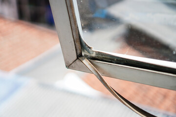 Poster - A close-up showcases an aging window frame, its metallic surface exhibiting corrosion and weathering. Reflections on the glass add depth, illustrating the passage of time and exposure to the elements.