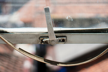 Poster - Close-up of an old window with a metal latch, capturing urban atmosphere. The textures of glass and aged metal evoke nostalgia and a glimpse into past with structural element detail.